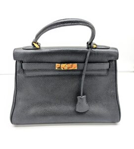 front view of black satchel with top handle and belted turnolck closure