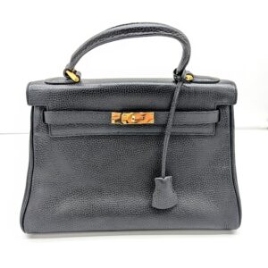 front view of black satchel with top handle and belted turnolck closure